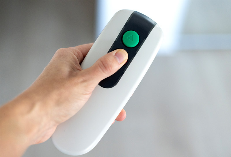 Finger pressing down button on remote that has an up and down button